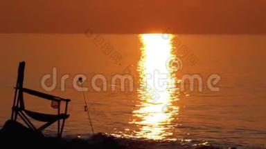 钓鱼椅和鱼竿的剪影在海边的日落小径上. 生活方式